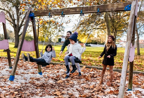 Preview: Happy family having fun with swings in autumn