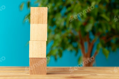 Preview: Wooden blocks on desk against blurred plant background