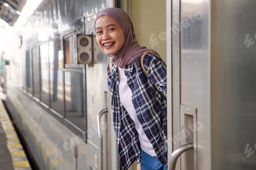 Preview: beautiful asian muslim woman standing at the train door with smiling face. traveling concept