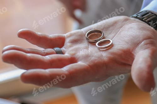 Preview: High angle selective focus shot of a person holding wedding rings