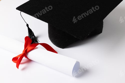 Preview: Image of graduation hat and diploma on white surface