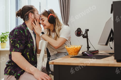 Preview: Young couple relaxing and showing love while playing video games on a personal computer