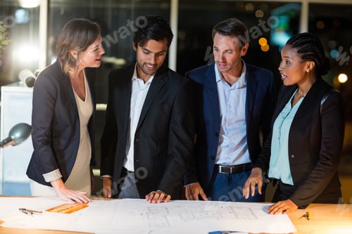 Preview: Group Of Businesspeople Discussing Over Blueprint In The Office