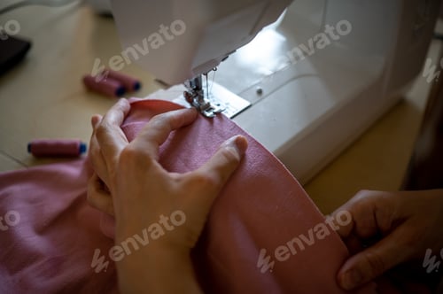 Preview: Detail. Sewing machine. . A young girl sews at home
