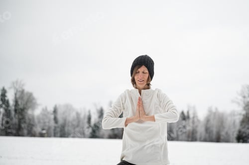 Preview: Peaceful young woman meditating outside in snowy nature