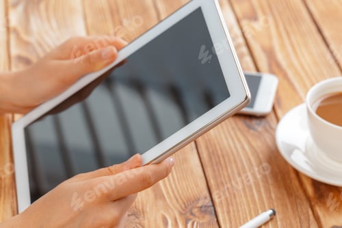 Preview: Close-up of young female hands holding digital tablet and drinking morning macchiato.
