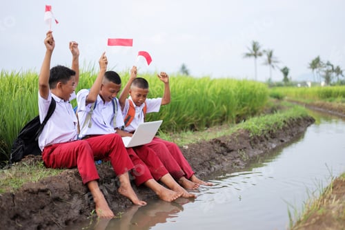 Preview: Elementary School Boys Cheering With Indonesian flags And Laptop While Sitting On Rice Field Area
