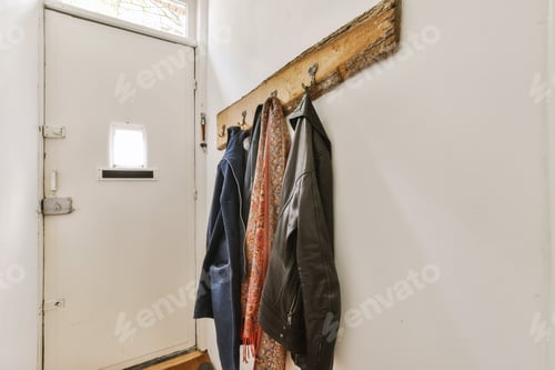 Preview: Jackets and Scarves Hanging Near a White Door