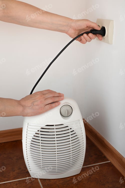 Preview: Female hand plugging space fan heater into wall power socket