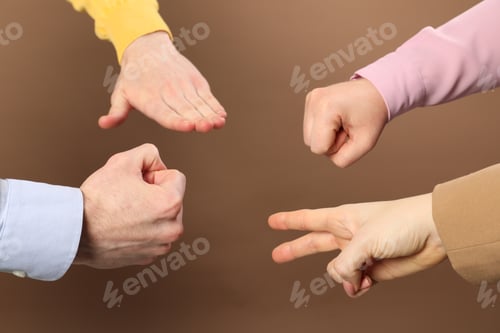 Preview: People playing rock, paper and scissors on brown background, closeup