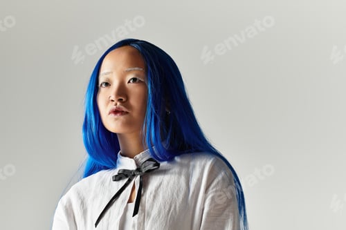 Preview: Young woman with vibrant blue hair in a stylish outfit on a grey background