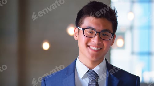 Preview: Portrait Of Confident Smiling Young Businessman Wearing Glasses Standing By Window In Office