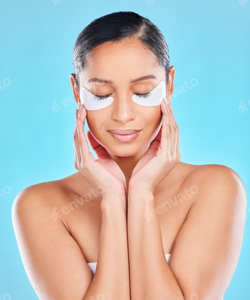 Preview: Studio shot of an attractive young woman wearing under eye patches against a blue background