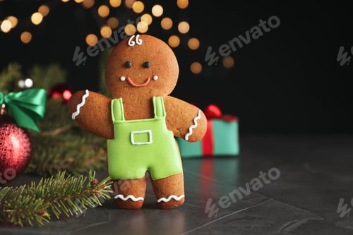 Preview: Gingerbread man on black table against blurred lights, closeup. Space for text