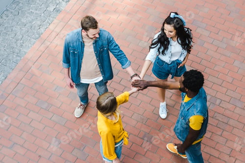 Preview: overhead view of positive multicultural friends putting hands together