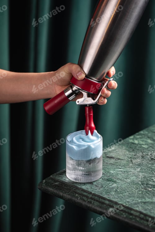 Preview: Cocktail with blue foam being poured from siphon