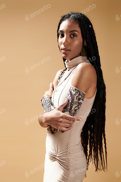 Preview: Stylish young woman with long braids showcasing elegance in a minimalist setting