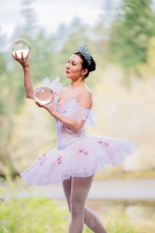 Preview: Ballerina in tutu holding crystal balls gracefully, with nature in the background. WA, USA
