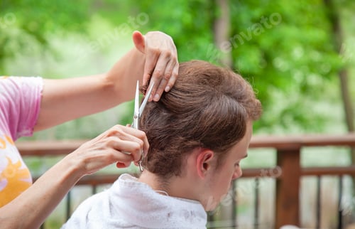 Preview: A teen boy gets a haircut from his mother outdoors during the pandemic