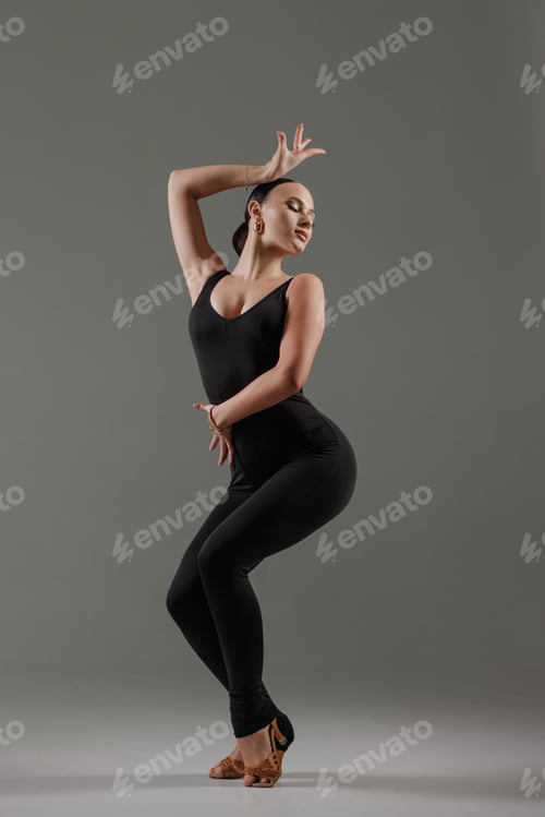 Preview: Stylish dancer posing in black bodysuit with expressive posture on gray background