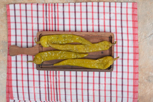 Preview: Pickled chili peppers on wooden board with tablecloth