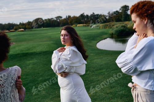 Preview: Stylish women embracing nature while showcasing summer fashion in a serene park setting