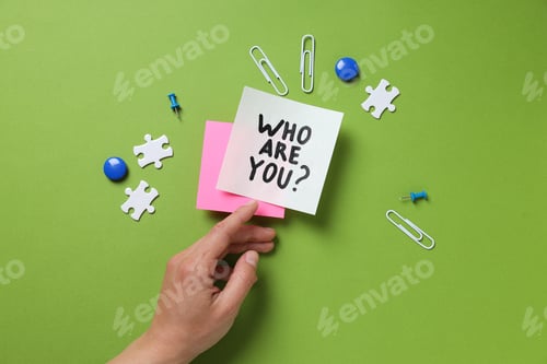 Preview: Stickers with text Who am I?, stationery and hand on green background, top view