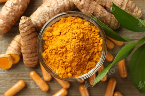 Preview: Turmeric capsules, powder, roots and green leaves on wooden table, flat lay