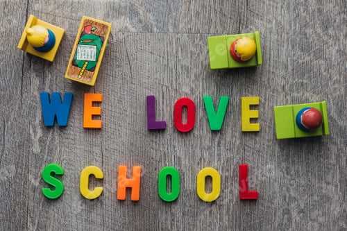Preview: Top down shot of the sentence "We love school" written in single letter on the ground.
