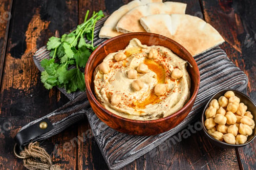 Preview: Hummus paste with pita bread, chickpea and parsley in a wooden bowl.