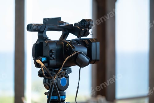 Preview: Professional video camera on tripod with sea view background