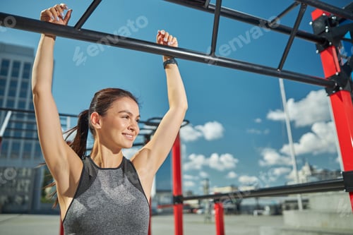 Preview: Positive delighted woman pulling up on the bar