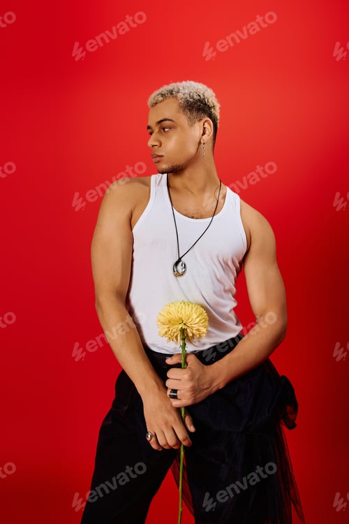 Preview: Young man with dyed hair poses confidently in a vibrant red studio setting