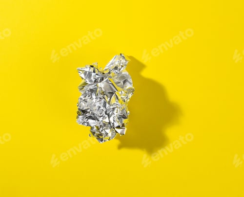 Preview: Crumpled piece of gray foil with shadow on yellow background