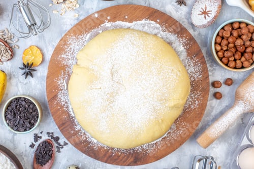 Preview: Close up view of raw pastry on round wooden board grater and set of foods on ice background
