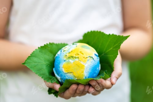 Preview: Kid holding small planet in hands against spring or summer green background. Ecology, environment