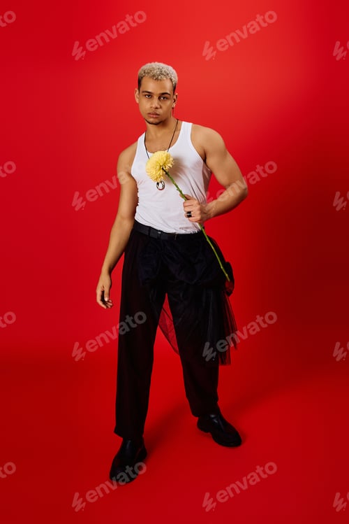 Preview: Trendy young man with dyed hair showcasing style in a vibrant red studio setting