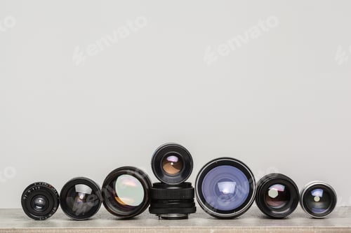 Preview: Various camera lenses arranged in a creative display on a wooden surface