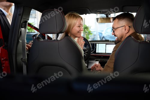 Preview: Young couple evaluates the interior of a new car
