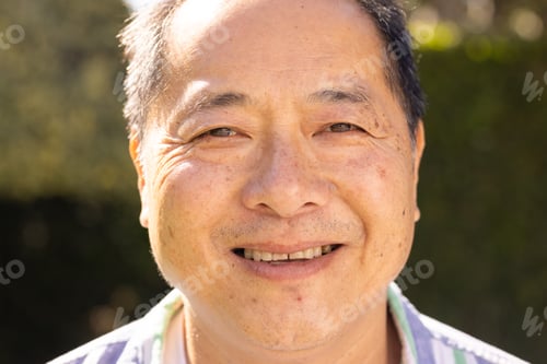 Preview: Smiling asian middle-aged man enjoying outdoor sunshine, close-up portrait in natural light