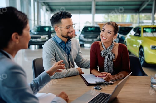 Preview: Happy couple having a meeting with salesperson at car dealership.