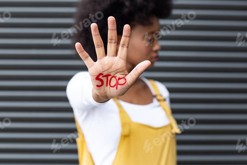 Preview: Portrait of mixed race woman making stop gesture with hand covered in writing