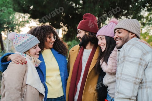 Preview: Group of young people smiling and talking outdoors with autumnal clothes. Multiracial friends having