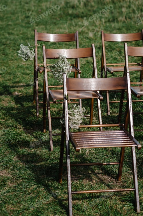 Preview: Wooden chairs for guests are decorated flowers and greens in the backyard banquet area. Wedding