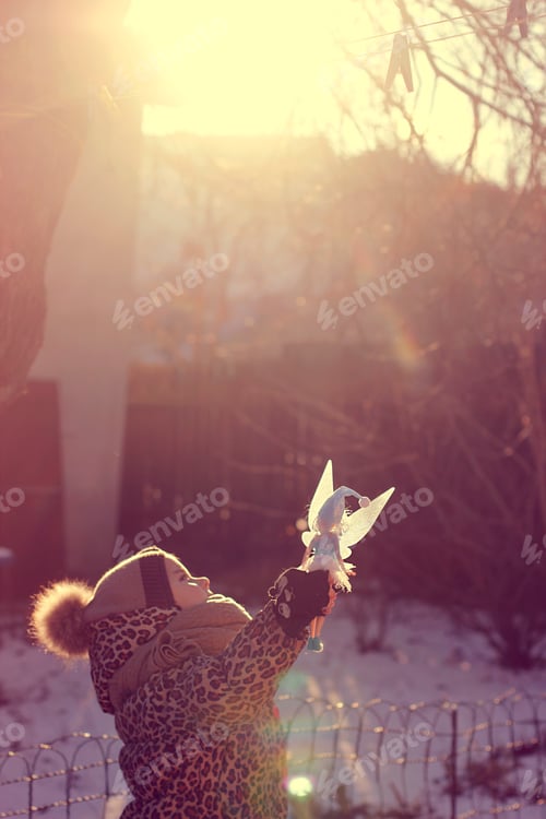Preview: Child Playing with Fairy Doll in Winter Sunlight