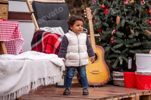 Preview: Toddler Plays Near Christmas Tree on Wooden Deck