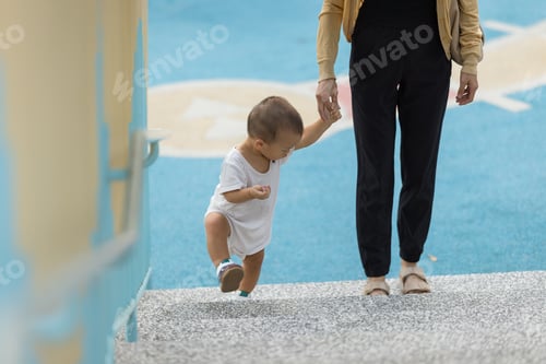 Preview: Mother helping baby walk up stairs at park