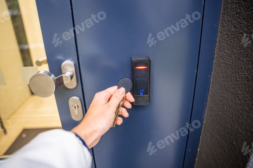 Preview: Close up view of person using a electric lock key fob to access a building via a reader of entry