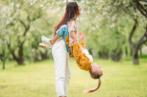 Preview: Family of mother and daughter in blooming cherry garden