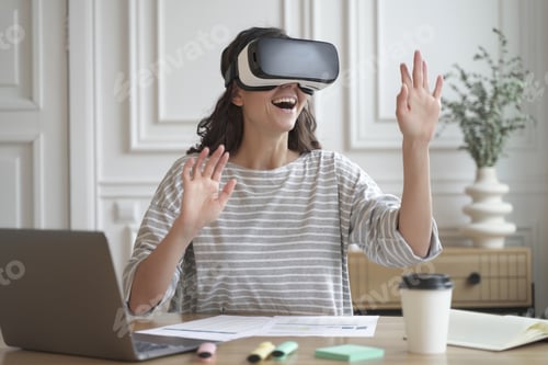 Preview: Excited amazed woman wearing VR glasses enjoying amazing virtual reality experience at work